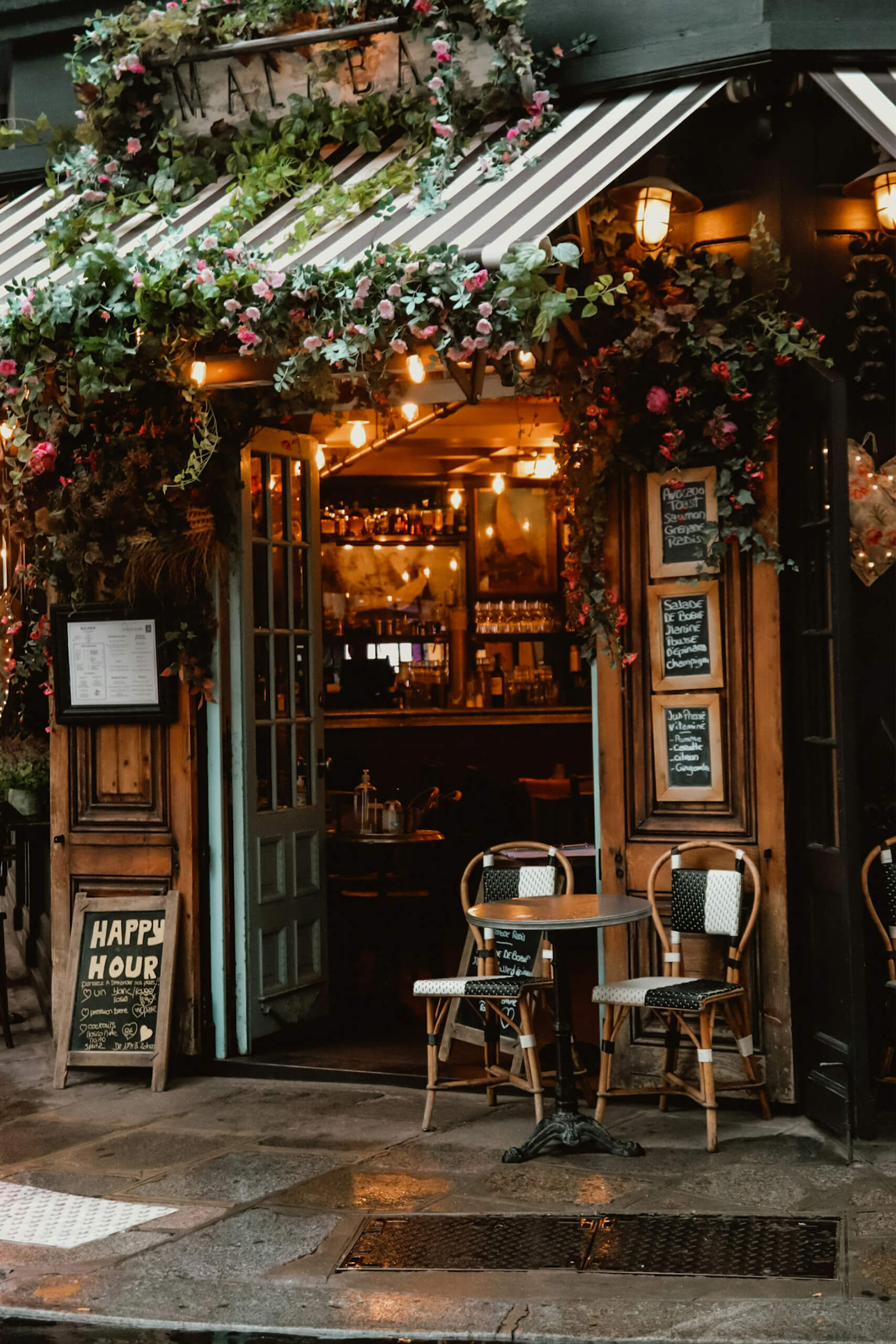 Cozy French café with flowers, bistro chairs, and warm lighting